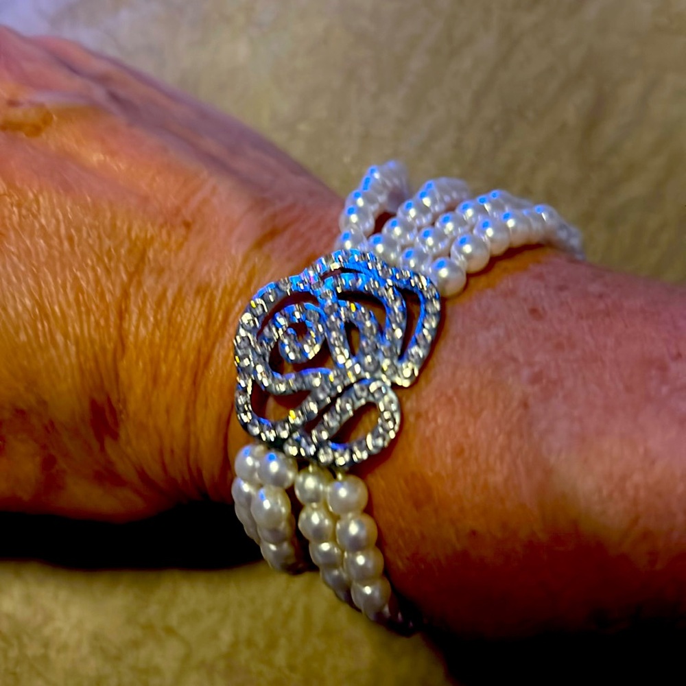 Four layered beaded pearl bracelet with a silver flower charm